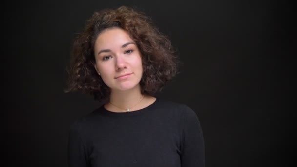 Primo piano ritratto di giovane donna affascinante con i capelli ricci sorridenti e guardando la fotocamera con disinvoltura — Video Stock