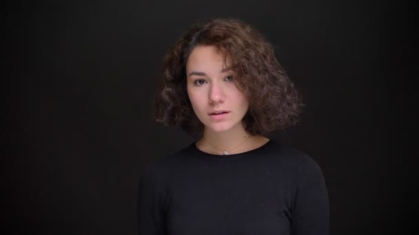 Closeup portrait of young attractive caucasian female model looking at camera and posing with the background isolated on black — Stock Video