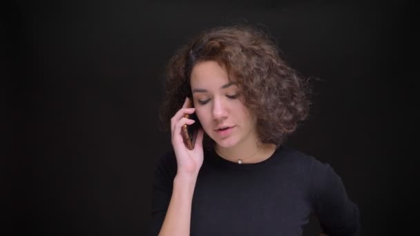 Gros plan portrait de jeune jolie femme caucasienne parlant au téléphone devant la caméra — Video