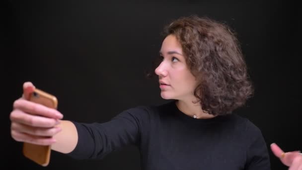 젊은 매력적인 여성 videoblogger 블랙에 고립 된 배경을 가진 그녀의 휴대 전화에서 라이브 스트리밍의 근접 촬영 초상화 — 비디오