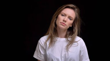 Sakin bir şekilde içine kamera siyah arka plan üzerine izlerken portre Genç beyaz uzun saçlı kızın başını eğik.