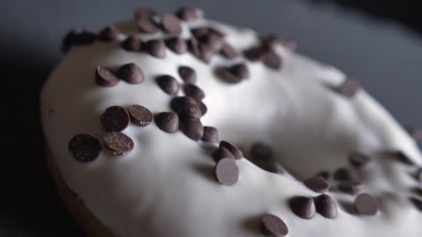 Primo piano mezzo colpo di deliziosa ciambella bianca smaltata con gocce di cioccolato che girano lentamente su sfondo grigio . — Video Stock