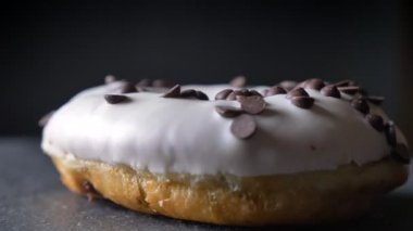 Çikolata parçaları yavaş yavaş gri tablo arka plan üzerinde iplik ile lezzetli camlı beyaz donut atış çember yakın çekim.