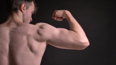 Yakın çekim onun kas pazı gösterilen ve gösteren gücünü siyah arka plan üzerine beyaz delikanlı arka portresi.