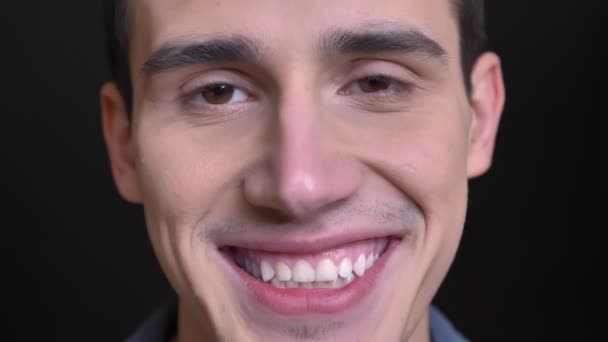 Closeup portrait of young caucasian male looking straight at camera and smiling with teeth happily — Stock Video
