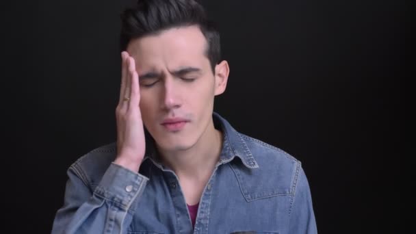 Closeup portrait of young caucasian man getting a headache and being frustrated exhausted in front of the camera