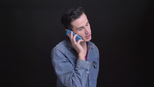 Gros plan portrait de jeune homme caucasien ayant une conversation sérieuse au téléphone — Video