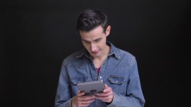 Genç beyaz yakışıklı adam arka plan üzerine siyah izole kamera önünde tablet tarama closeup portresi