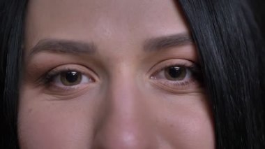 Doğruca kameraya gülümseyen yüz ifadesi ile arayan genç beyaz siyah saçlı kadın kahverengi gözleri closeup portresi