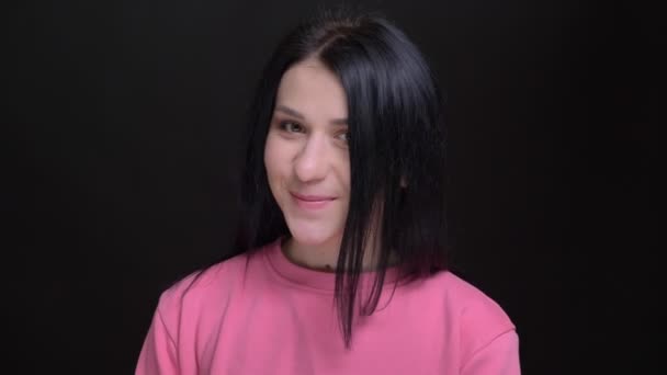 Nahaufnahme Porträt einer jungen hübschen Kaukasierin, die in die Kamera blickt und schüchtern lächelt — Stockvideo