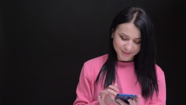 Primer plano retrato de joven hermosa mujer caucásica usando el teléfono reaccionando a los mensajes de redes sociales riendo y mirando a la cámara — Vídeo de stock