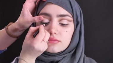 Göz makyajı için Müslüman kadında güzel: hijab siyah arka plan üzerine siyah kalem işi eller portresi.
