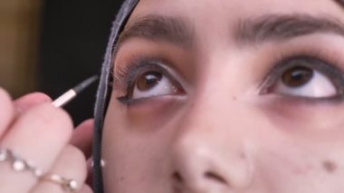 Erkek portresi yakın çekim hijab yukarı doğru siyah arka plan üzerine izlerken Müslüman kadın için ince fırçayla çizim siyah oku eller.