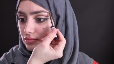 Kalıcı makyaj yapıyor ve siyah arka plan üzerine hijab kaşları çekici Müslüman kadın için fırçalama eller portresi