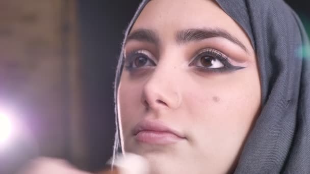 Portrét ženských rukou dělá make-up a zvýrazňovač pro mladé muslimské ženy v hidžábu na pozadí jasná světla. — Stock video
