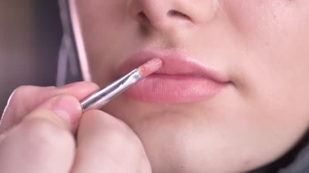 Primer plano de proceso de hacer maquillaje y poner lápiz labial rosa con cepillo delgado en la joven musulmana en hijab sobre fondo negro . — Vídeos de Stock