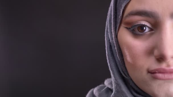 Close-up half-portret van een jonge moslimvrouw in hijab met modieuze make-up glimlachend in de camera op zwarte achtergrond — Stockvideo