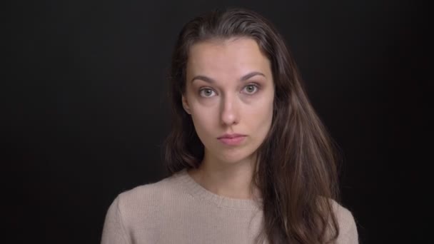 Nahaufnahme Porträt eines ernsthaften brünetten langhaarigen kaukasischen Mädchens, das auf schwarzem Hintergrund zustimmend in die Kamera nickt. — Stockvideo