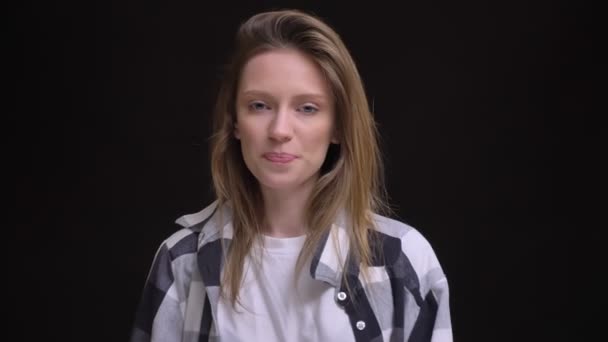 Portrait of joyful young caucasian long-haired girl in plaid shirt approvingly beckoning into camera on black background. — Stock Video