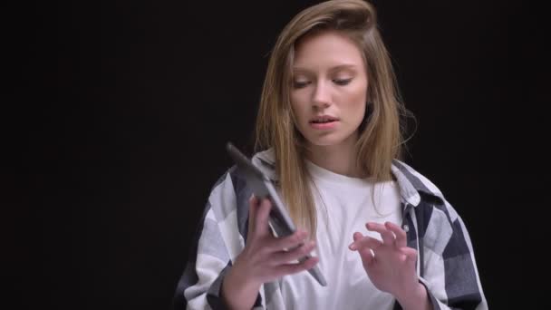 Retrato de rubia caucásica de pelo largo chica en camisa a cuadros con mucho gusto mostrando la pantalla verde de la tableta sobre fondo negro . — Vídeo de stock