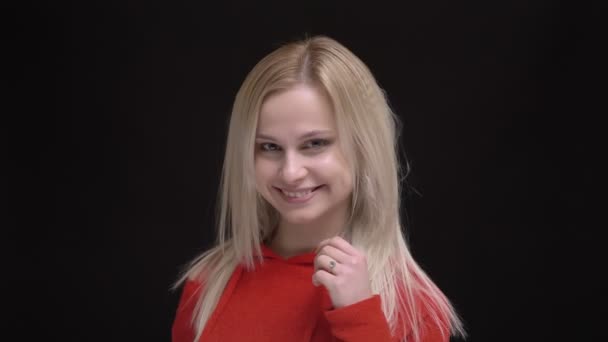 Flirtingly 黒の背景上にカメラに髪を振って赤いセーターの白髪白人少女の肖像画 — ストック動画