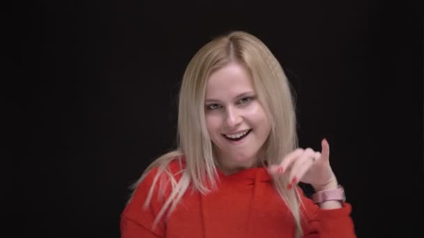 Portrait of young white-haired caucasian girl in red sweater strangely dancing and singing on black background. — Stock Video