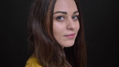 Kamera ve içine gülümsüyor siyah zemin üzerine sarı kazaklı uzun saçlı esmer kız portresi yakın çekim döner.