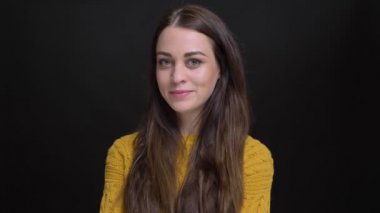 Sarı kazaklı el ile uzun saçlı esmer kız portresi çene alçakgönüllü içine kamera siyah arka plan üzerinde gülümseyen.