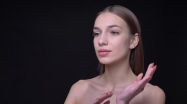 Siyah arka plan üzerine el hareketleri yapıyor mesafe içine izlerken çıplak makyaj ile genç ve ince beyaz kız portresi.