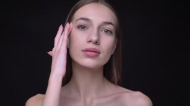 Genç ve ince beyaz kız çıplak makyaj yumuşak yüzünü siyah arka plan üzerine dokunmadan kamera içine izlerken ile portresi.