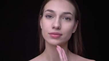 Genç ve ince beyaz kız kameraya izliyor ve yüzünü hakkı olan dokunmadan çıplak makyaj ile siyah arka plan üzerine el.