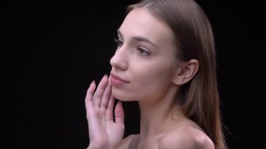 Genç ve yumuşak yüzünü dokunaklı ve sakin bir şekilde içine kamera siyah arka plan üzerine izlerken çıplak makyaj ile ince beyaz kız.