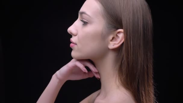 Portrait de profil de jeune fille caucasienne mince avec maquillage nu touchant tendrement son cou sur fond noir . — Video