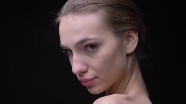 Yakın çekim portre profil taşıma ve ciddi kamera siyah arka plan üzerine içine izlerken çıplak makyaj ile ince beyaz kızın.