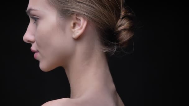 Retrato de joven y delgada chica caucásica con maquillaje desnudo moviéndose lentamente y mirando en cámara sobre fondo negro . — Vídeos de Stock