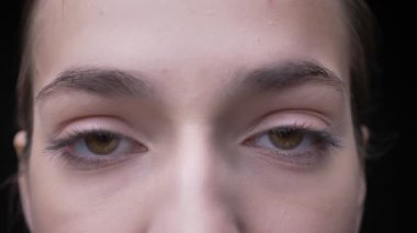 Göz-çıplak makyaj ile genç ve ince beyaz kız portresi gözlerini açar ve sakin bir şekilde içine kamera siyah arka plan üzerine saatler