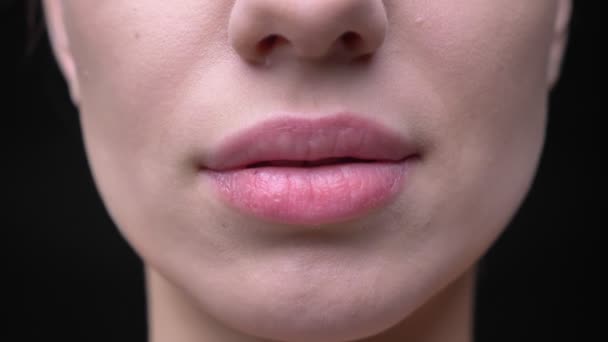 Close-up labios-retrato de joven y delgada chica caucásica con maquillaje desnudo sobre fondo negro . — Vídeos de Stock