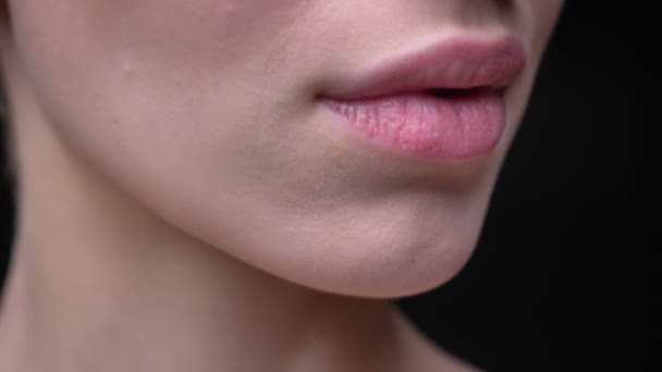 Close-up portrait of young and slim caucasian girl with nude make-up slowly opens her lips on black background. — Stock Video