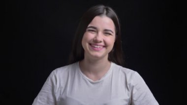 Memnuniyetle kamera siyah arka plan üzerine içine gülerek kilolu esmer beyaz kız portresi.