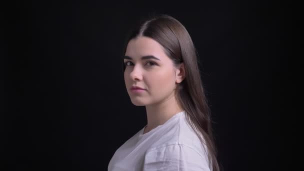 Portrait in profile of young overweight brunette caucasian girl watches smilingly into camera on black background. — Stock Video