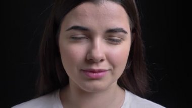 Yakın çekim portre genç kilolu esmer beyaz kız gülümseyerek kamera siyah arka plan üzerine içine izlerken.