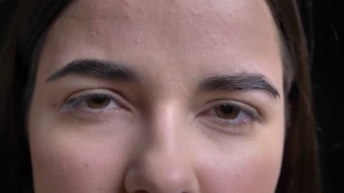 Yakın çekim genç kilolu esmer beyaz kız kamera siyah arka plan üzerine içine sakince izlerken göz portresi.