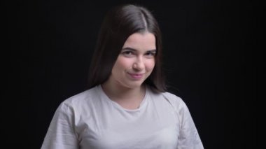 Genç kilolu esmer beyaz kız utanarak kamera siyah arka plan üzerine içine izlerken portresi.