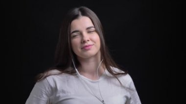 Genç kilolu esmer beyaz kız gülümseyerek siyah arka plan üzerine dans kulaklık portresi.