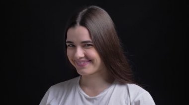 Genç kilolu esmer beyaz kız utanarak kamera siyah arka plan üzerine içine gülerek portresi.