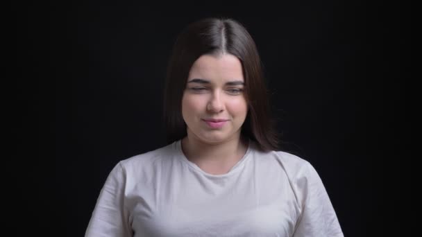 Portrait de jeune fille caucasienne brune en surpoids regardant timidement dans la caméra sur fond noir . — Video