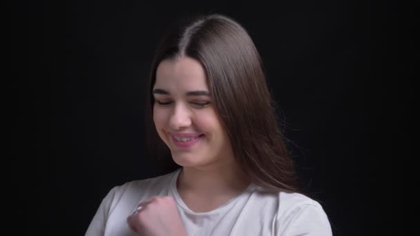 Портрет молодої надмірної ваги брюнетки кавказької дівчини смиренно сміється в камеру на чорному тлі . — стокове відео