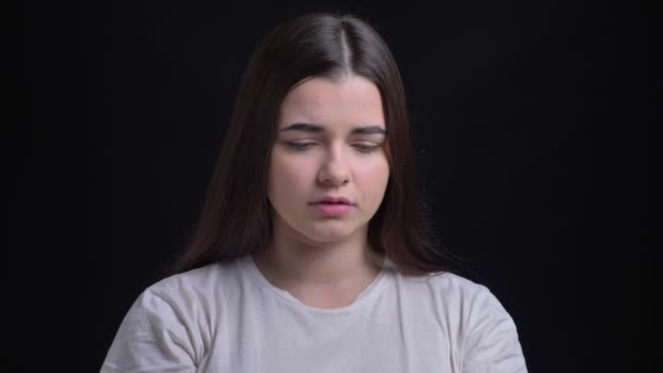 Портрет молодої надмірної ваги брюнетки кавказької дівчини, яка на жаль дивиться в камеру на чорному тлі . — стокове відео