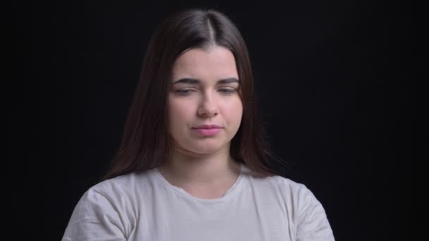 Retrato de una joven morena caucásica con sobrepeso mirando miserablemente a la cámara sobre fondo negro . — Vídeos de Stock