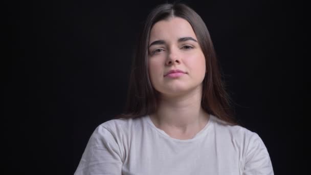 Portret van overgewicht brunette Kaukasische meisje kijken zorgvuldig op zwarte achtergrond. — Stockvideo